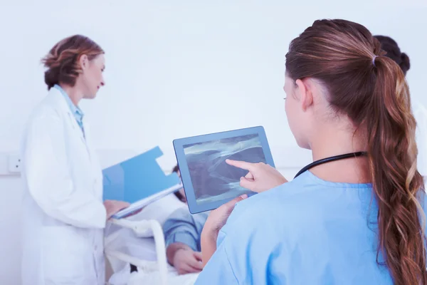 Sammansatt bild av läkare titta på xray på Tablet PC — Stockfoto