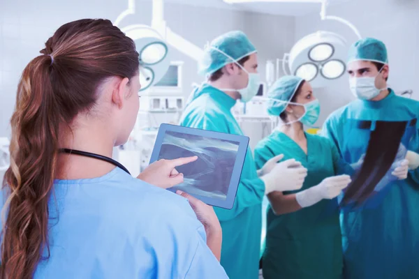 Composite image of doctor looking at xray on tablet — Stock Photo, Image