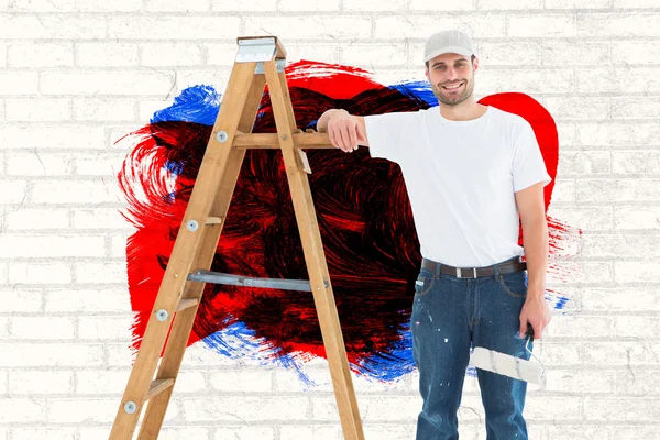 Hombre feliz con rodillo de pintura de pie por escalera —  Fotos de Stock