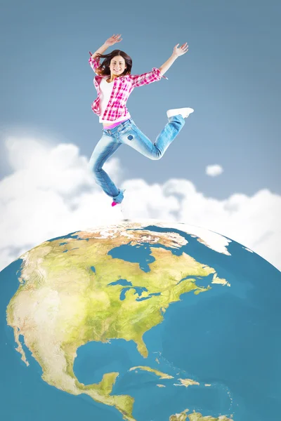 Composite image of casual brunette jumping and smiling — Stock Photo, Image