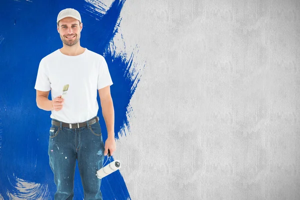 Happy man holding paint roller and paintbrush — Stock Photo, Image