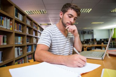 Student studying in the library with laptop clipart