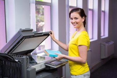 Student photocopying her book in the library  clipart