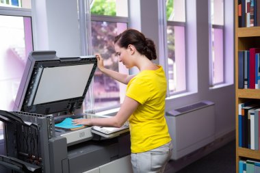 Student photocopying her book in the library  clipart