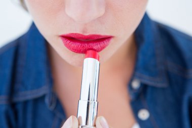 Woman putting red lipstick  clipart
