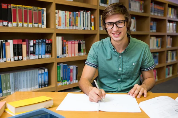 Studentin sitzt in Bibliothek und schreibt — Stockfoto