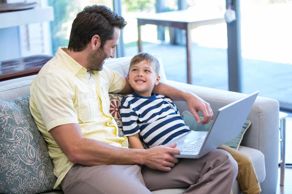 Pai e filho usando laptop no sofá — Fotografia de Stock