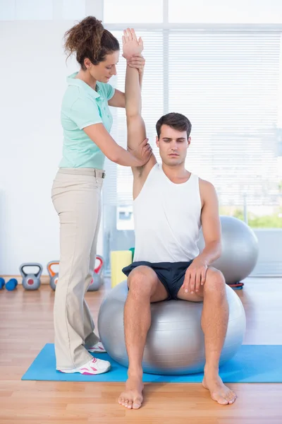 Man stretching his arm with trainer — Stock Photo, Image