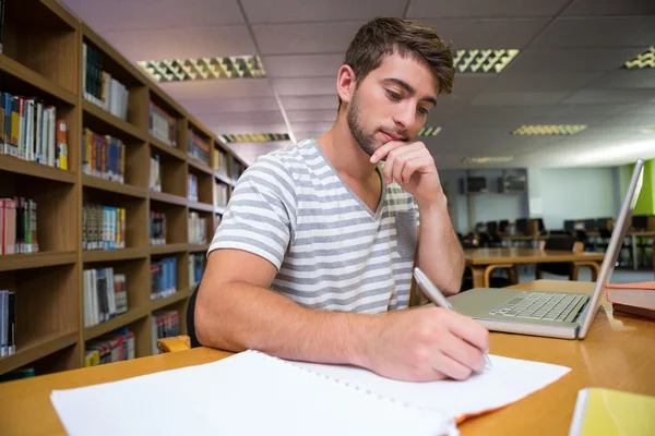 Φοιτητής που σπουδάζει στη βιβλιοθήκη με laptop — Φωτογραφία Αρχείου