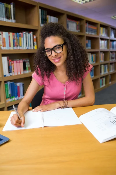 Studentin sitzt in Bibliothek und schreibt — Stockfoto