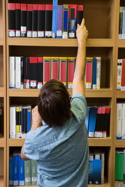 Student picking a book from shelf — Stock Photo, Image