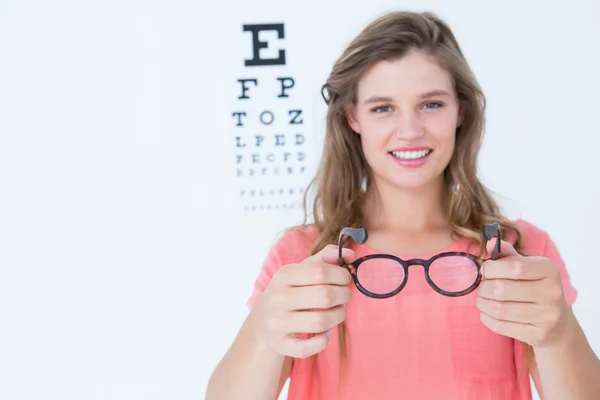 Bederní, ukazující brýle vedle oční test — Stock fotografie