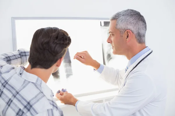 Доктор дивиться рентгенівські промені зі своїм пацієнтом — стокове фото
