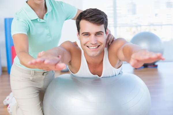 Trainer with man on exercise ball — Stock Photo, Image