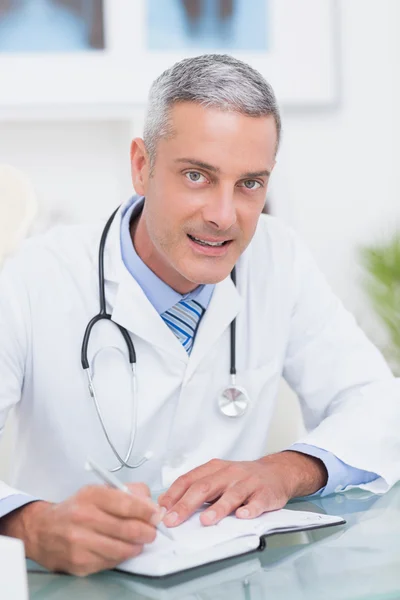 Doctor escribiendo en el diario en su escritorio —  Fotos de Stock