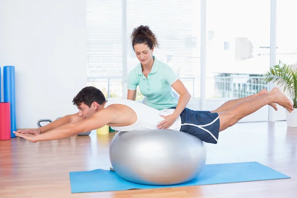 Trainer with man on exercise ball — Stock Photo, Image