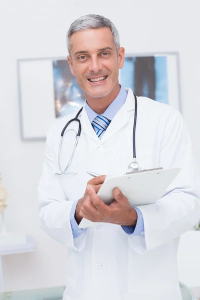 Médico segurando prancheta e sorrindo — Fotografia de Stock