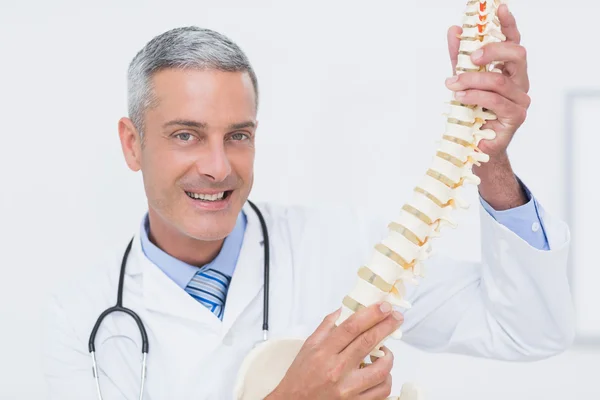 Médico sorridente mostrando coluna anatômica — Fotografia de Stock