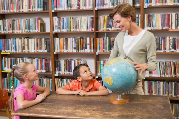 Allievi e insegnanti che guardano il globo in biblioteca — Foto Stock