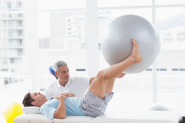 Терапевт помогает пациенту с мячом для упражнений — стоковое фото