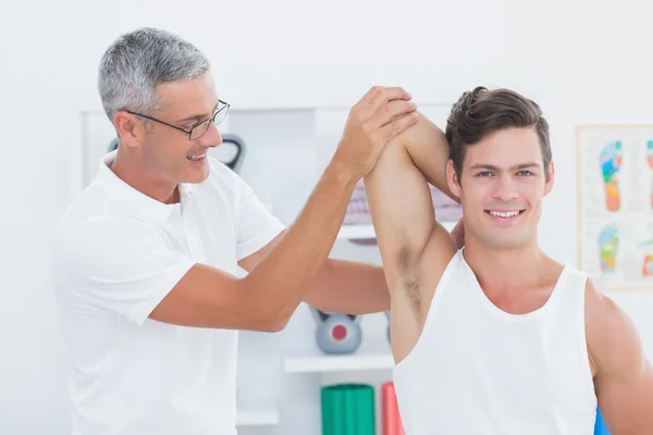 Doctor estirando un brazo de hombre joven —  Fotos de Stock