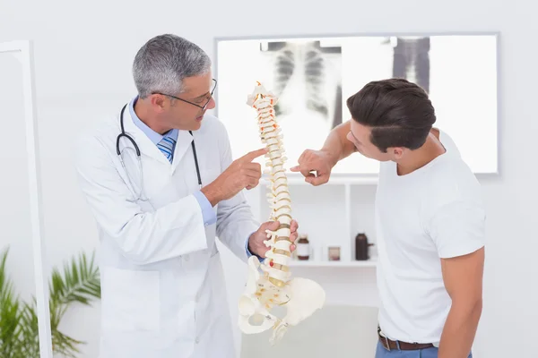 Médico explicando columna anatómica al paciente — Foto de Stock