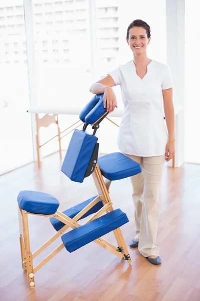Terapeuta sorridente in piedi con sedia da massaggio — Foto Stock