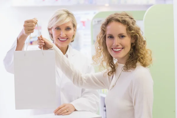 Farmacéutico y cliente sosteniendo bolsa de papel — Foto de Stock