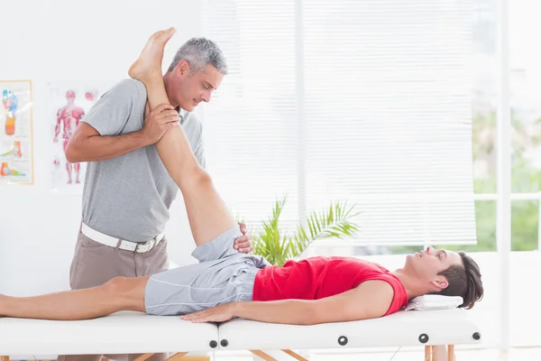 Физиотерапевт делает растяжку ноги своему пациенту — стоковое фото