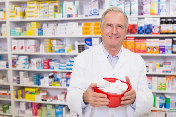 Senior pharmacist holding bowl of medicines — Stock Photo, Image