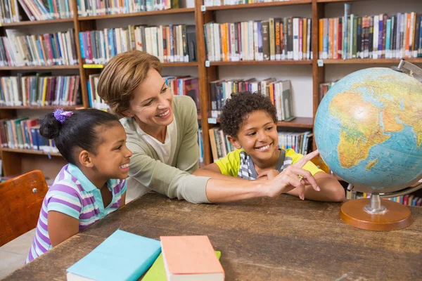 Leerlingen en leraar kijken naar globe in bibliotheek — Stockfoto