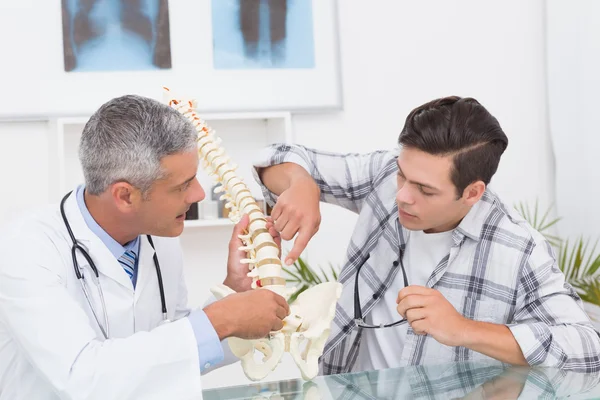 Médico explicando la columna vertebral a un paciente — Foto de Stock