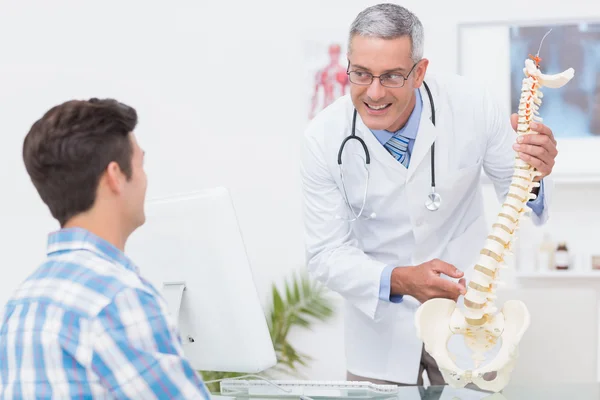 Arzt erklärt Patienten ein Wirbelsäulenmodell — Stockfoto