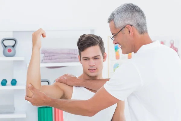 Doctor stretching a young man arm — Stock Photo, Image