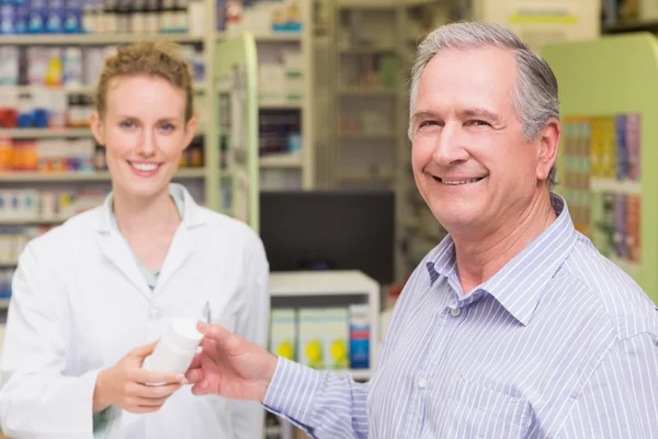 Farmacêutico e cliente sorrindo uma câmera — Fotografia de Stock