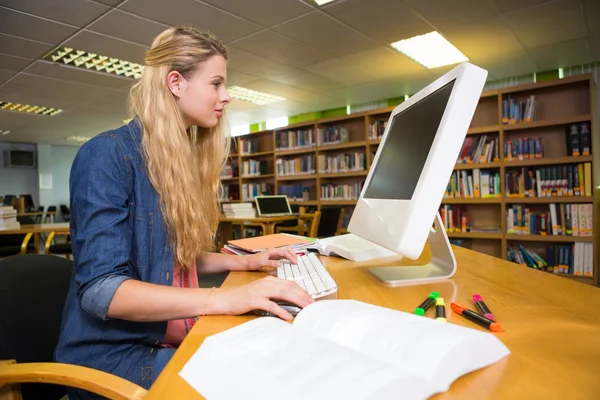 Student studuje v knihovně s počítačem — Stock fotografie