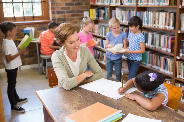 Nauczyciel pomaga uczniów w bibliotece — Zdjęcie stockowe