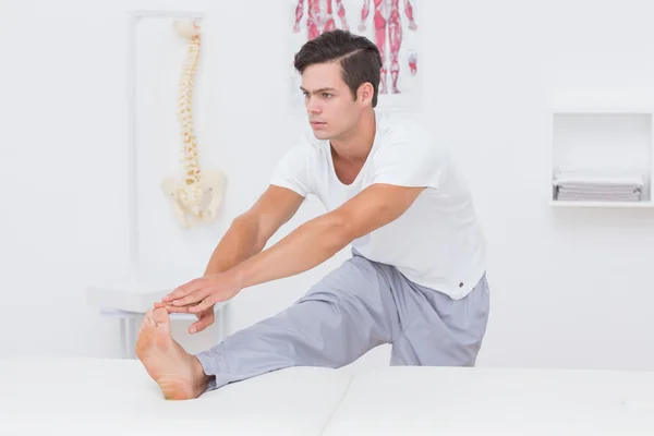 Paciente estirando su pierna en la cama — Foto de Stock