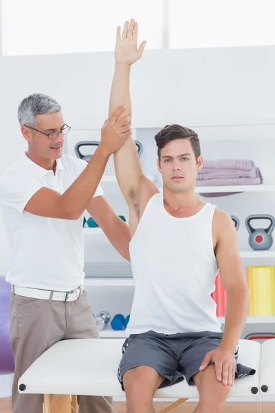 Doctor raising a young man arm — Stock Photo, Image