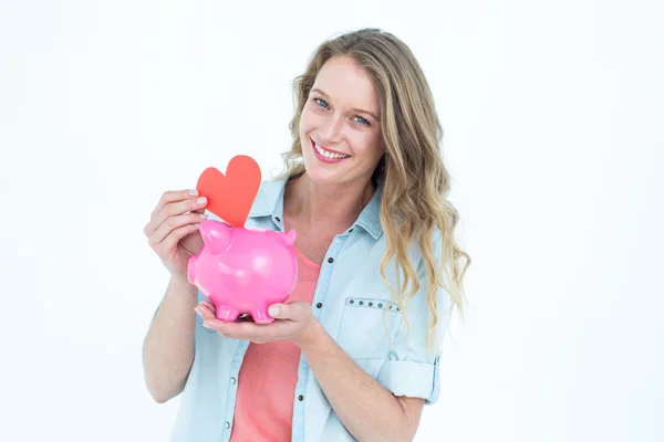 Woman holding piggy bank and red heart — Stock Photo, Image