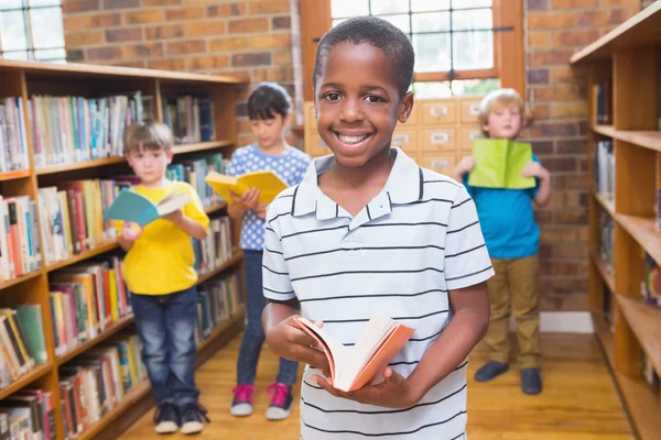 Ученик улыбается перед камерой в библиотеке — стоковое фото