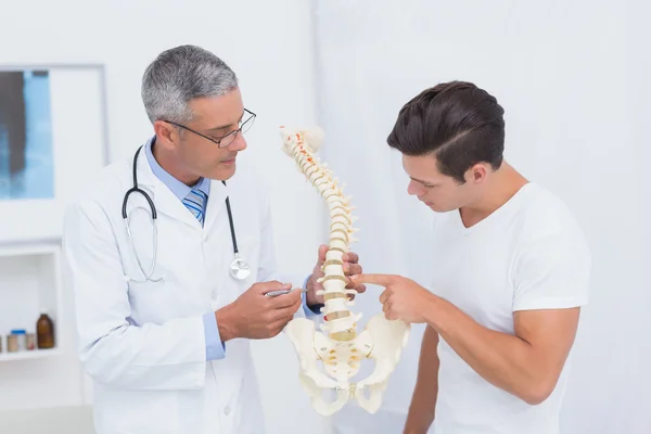 Médico explicando columna anatómica al paciente — Foto de Stock