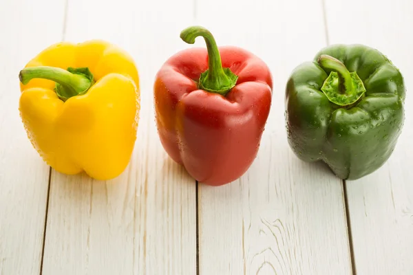 Tres pimientos en la tabla de cortar — Foto de Stock