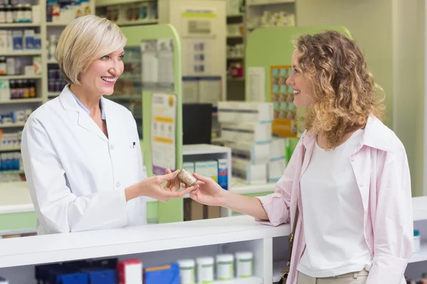 Pharmacist and costumer holding medicine jar — Stock Photo, Image