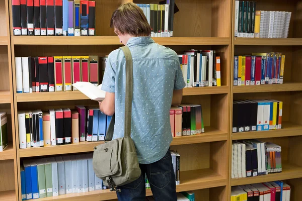 Student läsa bok i biblioteket — Stockfoto