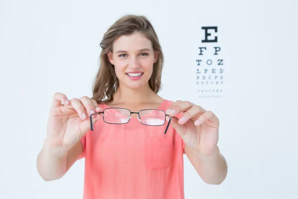 Hipster mostrando óculos ao lado de um teste ocular — Fotografia de Stock