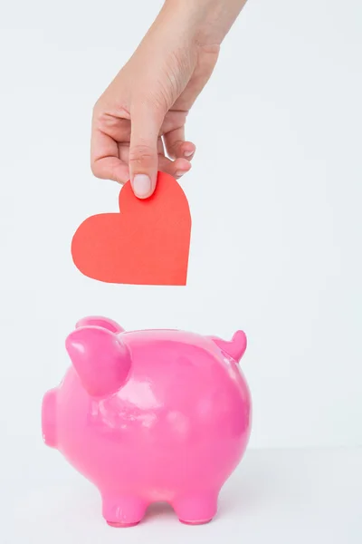 Woman holding piggy bank and red heart — Stock Photo, Image