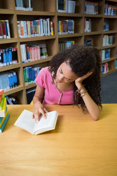 Красивая студентка учится в библиотеке — стоковое фото