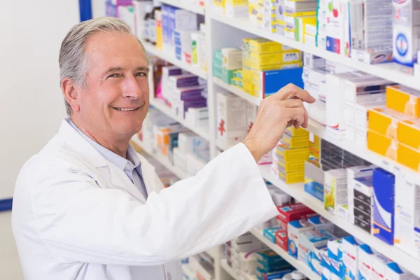 Senior apotheker innemen van medicijnen van plank — Stockfoto