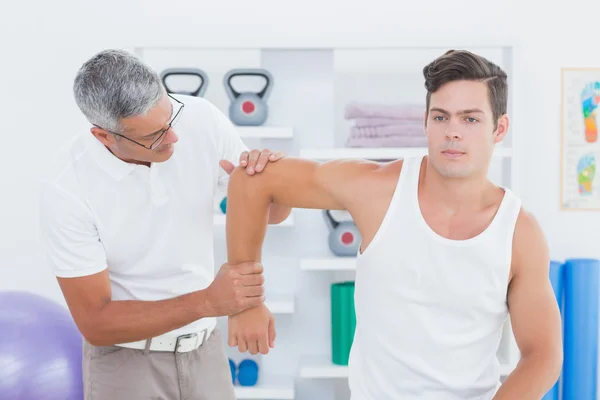 Doctor stretching a young man arm — Stock Photo, Image